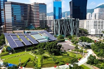 Cityscape with solar panels on a building roof and a green park, highlighting supply chain sustainability.